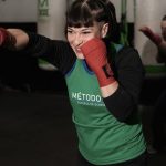 Energetic woman practicing boxing in a Buenos Aires gym with classmates.